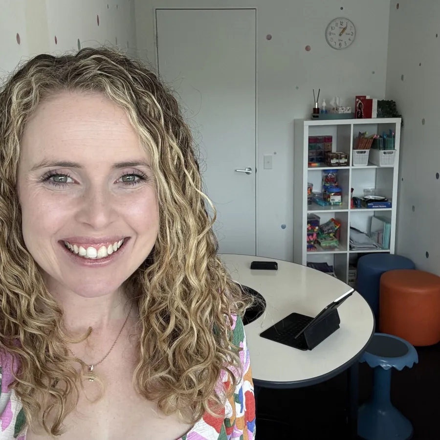 Dominique Solia in her Robina clinic room, with the teaching table and shelves of literacy resources behind her
