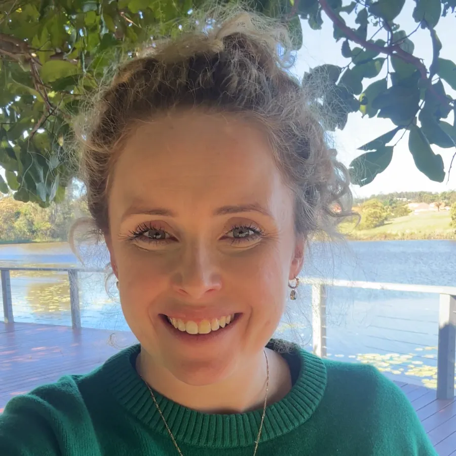 Dominique Solia smiling outdoors beside a lake on the Gold Coast